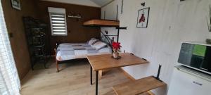 a small bedroom with a bed and a table with a television at Les Milles Bottes et ses Roulottes in Encausse-les-Thermes