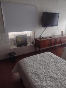 a bedroom with a bed and a flat screen tv at Casa Turística Camitas Inn in Bogotá