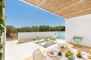 un patio con mesa y sillas y una piscina en Masseria Pensato, en Savelletri di Fasano