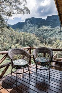 two chairs on a deck with a view of mountains at Refúgio Ecológico Pedra Afiada in Praia Grande