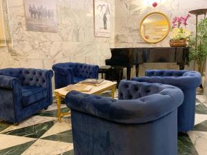 una stanza con sedie blu, tavolo e pianoforte di Hotel Raffaello - Self Check-in Free a Urbino
