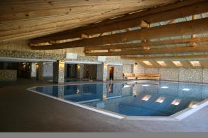 a large swimming pool in a building with a wooden ceiling at Cheile Gradistei Fundata Resort in Fundata