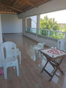 Cantinho da paz jesus nazareno في Gamela: غرفة بها كراسي بيضاء وطاولة عليها ورد