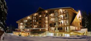 a large building in the snow at night at Hotel Iceberg Borovets in Borovets