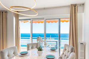 een eetkamer met een tafel en uitzicht op de oceaan bij Close to Monaco - Amazing Bay View - Free Parking in Saint-Antoine