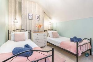 two beds in a bedroom with pink and blue towels at Home AWey - Holiday home near harbour in Weymouth