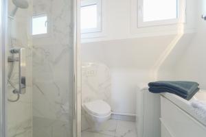 een witte badkamer met een toilet en een douche bij Quiet cosy and bright apartment with Terrace in Saint-Ouen