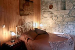 1 dormitorio con pared de piedra, 1 cama y 2 lámparas en Casa de Marlães, en Lousada