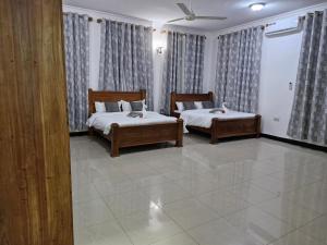 a bedroom with two beds and curtains at 64 ZENJ HOUSE Luxury Airport B&B in Mbweni