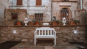 a white bench sitting in front of a brick wall at Casa Tarducci in Urbania