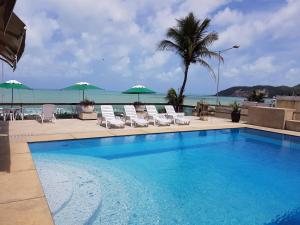 una piscina con sillas y sombrillas y el océano en Mansão a Beira Mar - HR Corretora, en Natal