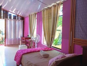 a bedroom with a bed with pink walls and a window at KORYARES HAUS-TAMBOPATA in Puerto Maldonado