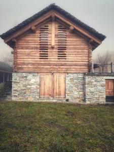 a house with wooden doors and a stone wall at Rustico Valgrazia in Molare