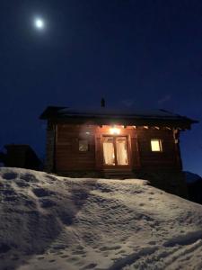 a cabin with a window in the snow at night at Rustico Valgrazia in Molare +8 photos