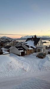 un patio cubierto de nieve con una casa y un coche en Arctic Loft en Skjervøy