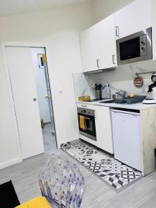 a kitchen with white cabinets and a sink and a chair at Charmant studio près de Roissy CDG in Le Mesnil-Amelot