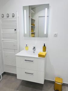 a white bathroom with a sink and a mirror at Charmant studio près de Roissy CDG in Le Mesnil-Amelot