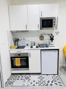 a white kitchen with a sink and a stove at Charmant studio près de Roissy CDG in Le Mesnil-Amelot