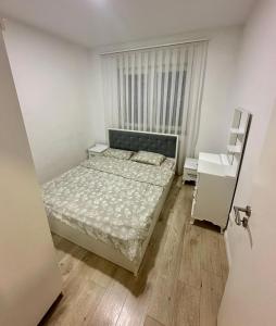 a small bedroom with a bed and a window at Lovely Family Apartment in Ferizaj