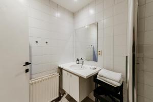 a white bathroom with a sink and a mirror at Cathedral view apartment in Antwerp +45 photos