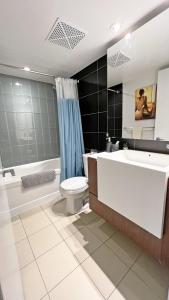 a bathroom with a tub and a toilet and a sink at Stunning Luxurious LakeView Condo by CN Tower in Toronto