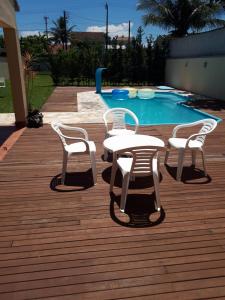 a white table and chairs next to a swimming pool at PARAISO FAMILIAR- Piscina- Pontal do Sul - PR in Pontal do Paraná