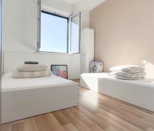 Duas camas num quarto branco com uma janela em Love Dubrovnik Hostel em Dubrovnik