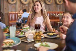 une femme et deux enfants assis à une table et mangeant de la nourriture dans l'établissement Great Wolf Lodge Bloomington, à Bloomington