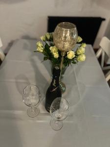 a table with three wine glasses and a vase with flowers at Apartament Starówka in Nowy Sącz