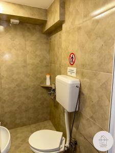 een badkamer met een toilet en een bord aan de muur bij Prishtina Center Apartment 3 in Pristina