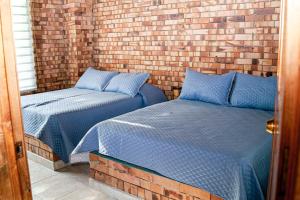 two beds in a room with a brick wall at Rancho Grande in Silvania