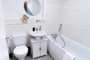 uma casa de banho com um WC, um lavatório e um espelho. em Hewitt House Business Contractor em Peterborough