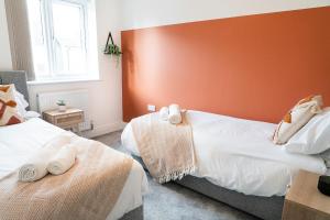 um quarto com 2 camas e uma parede vermelha em Hewitt House Business Contractor em Peterborough