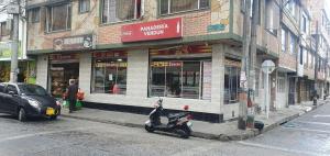 a scooter parked in front of a store on a street at VERDUN ROOMS in Bogotá