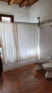 a bathroom with a white shower curtain and a toilet at Casa Maca in Mendoza