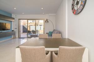 Un comedor con una mesa y sillas y un reloj. en Casa Catalina, en Los Alcázares