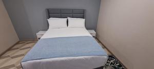 1 cama con sábanas blancas y manta azul en HARESCA LUXURY Accommodation Bellville, en Ciudad del Cabo