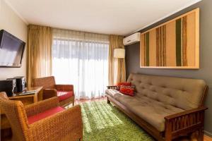 a living room with a couch and a television at Suites El Golf San Sebastian 2711 Las Condes in Santiago