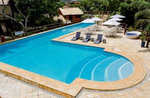 a large swimming pool with lounge chairs and umbrellas at Pontal da Ferradura in Búzios