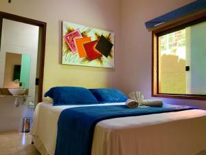 1 dormitorio con cama con sábanas azules y ventana en Pousada Recanto do Chalé Ltda en Macacos