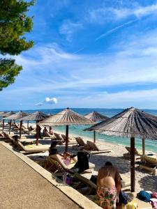 a group of people sitting on the beach with umbrellas at Apartment with free parking spot and sea view in Podstrana