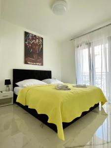 a bedroom with a bed with a yellow blanket on it at Apartment Emanuel in Podstrana