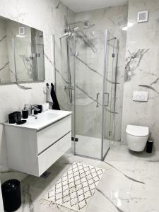 een witte badkamer met een douche en een wastafel bij Apartment Emanuel in Podstrana