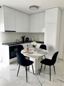 a white kitchen with a white table and chairs at Apartment with free parking spot and sea view in Podstrana