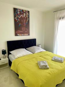 een slaapkamer met een groot bed en een gele deken bij Apartment Emanuel in Podstrana