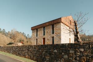 un edificio de piedra detrás de una pared de piedra en A casa de Foratoxo, en A Bana