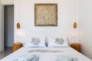 a white bed with two pillows and a picture on the wall at House of Harmony - Beachfront in Antiparos