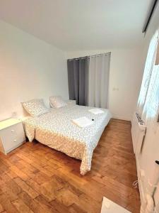 a bedroom with a bed and a wooden floor at L'adorable Maison des Clients 15min de Paris in Houilles