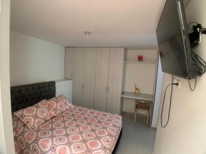 Dormitorio pequeño con cama y TV en Apartaestudio en a Milla de oro, restaurantes, Centros comerciales, clínica Keralty, en Ibagué