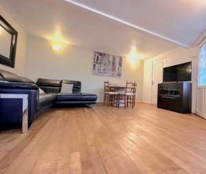 ein Wohnzimmer mit einem Sofa und einem Tisch in der Unterkunft L'adorable Maison des Clients 15min de Paris in Houilles